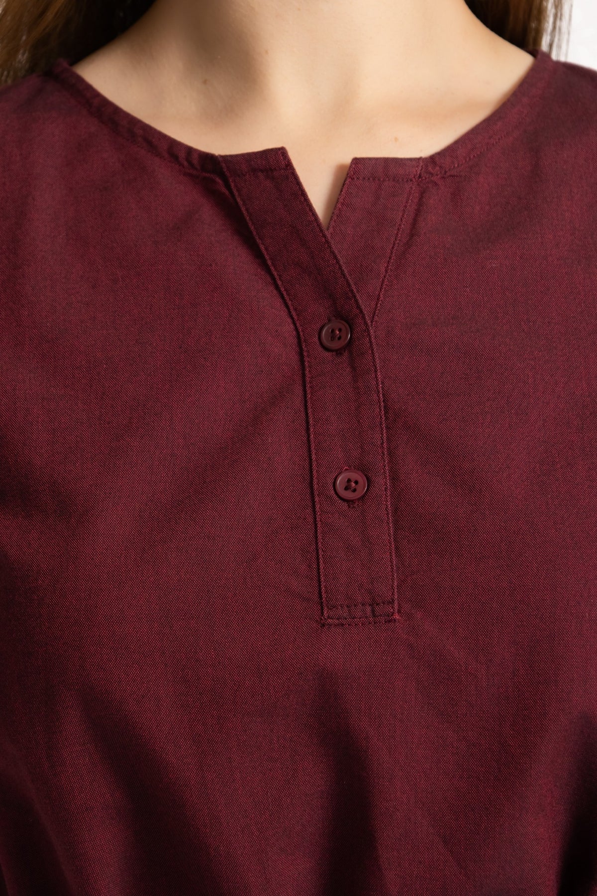 Close-up of the notch neckline and button detail on a burgundy linen cotton dress
