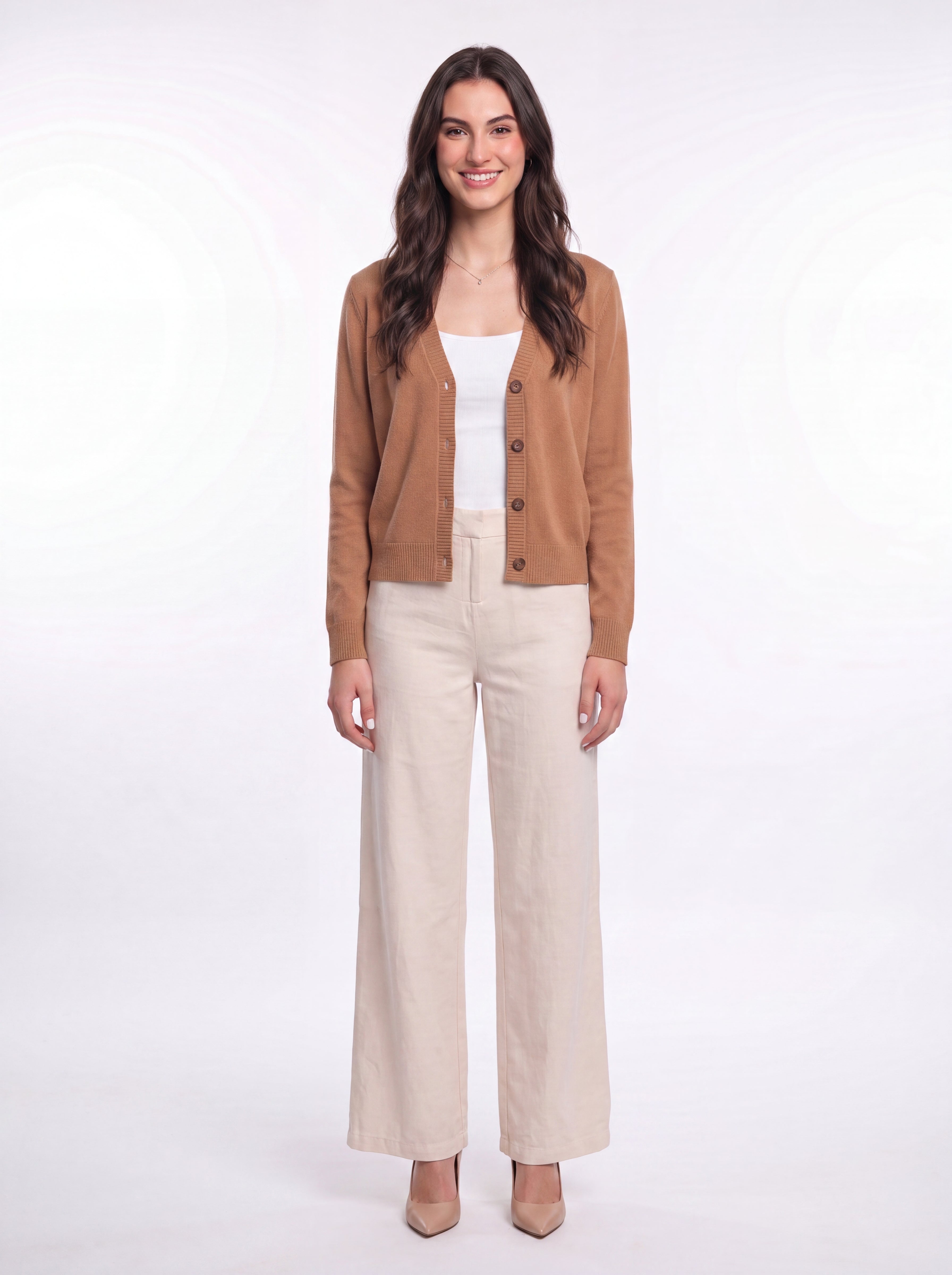 Full-length front view of woman wearing a cinnamon tan Cashmere-Merino Cardigan over a white top and cream wide-leg trousers
