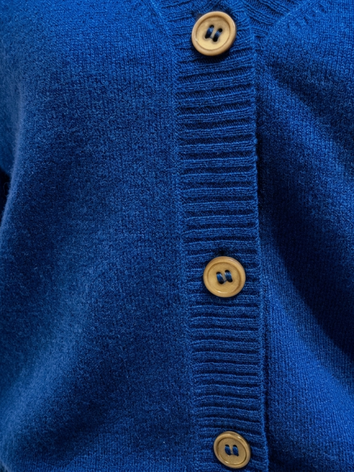 Close-up of cobalt blue Cashmere-Merino Cardigan front button closure with light horn-look buttons