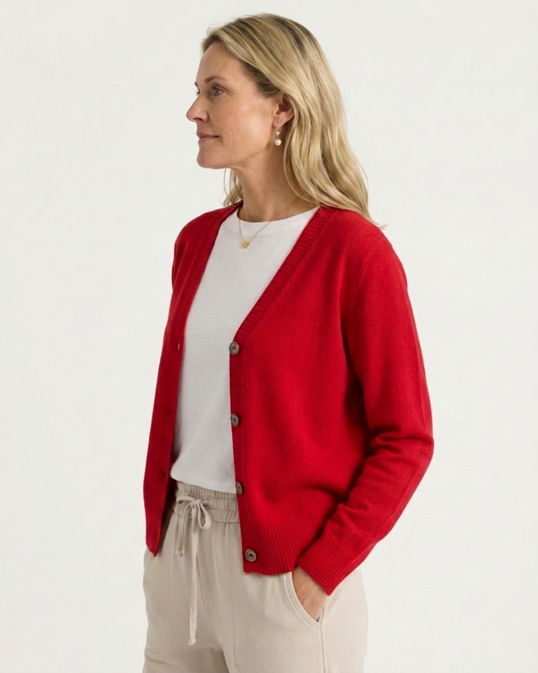 Woman wearing the red Cashmere-Merino cardigan over a white tee with beige drawstring trousers, side-on view