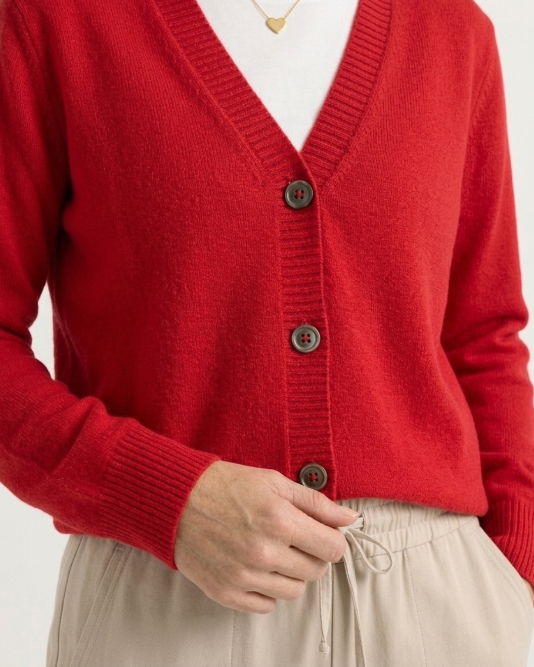 Cropped view of the buttoned red Cashmere-Merino cardigan showing the V-neckline, button placket and ribbed hem