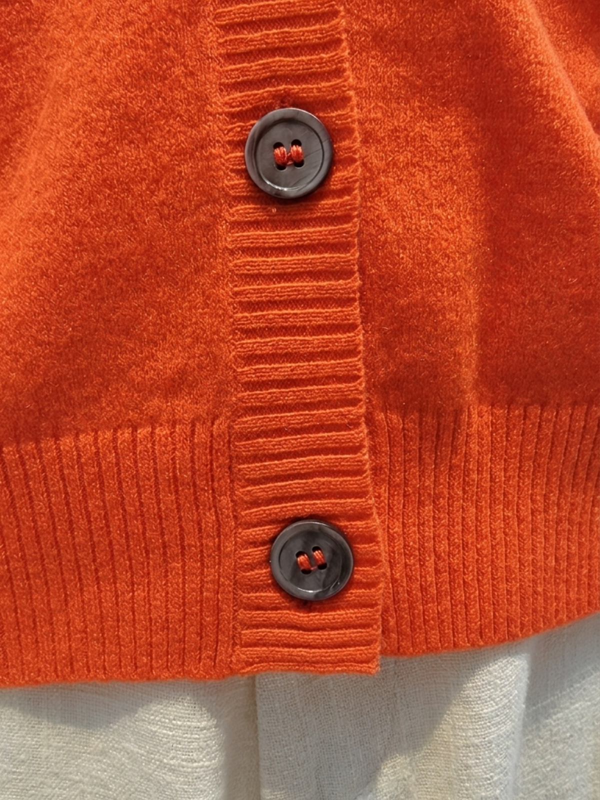 Close-up of scarlet red Cashmere-Merino Cardigan showing ribbed hem, cuffs and dark buttons