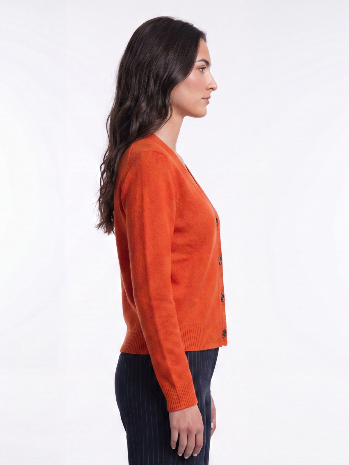 Side profile of woman wearing a scarlet red Cashmere-Merino Cardigan with dark trousers