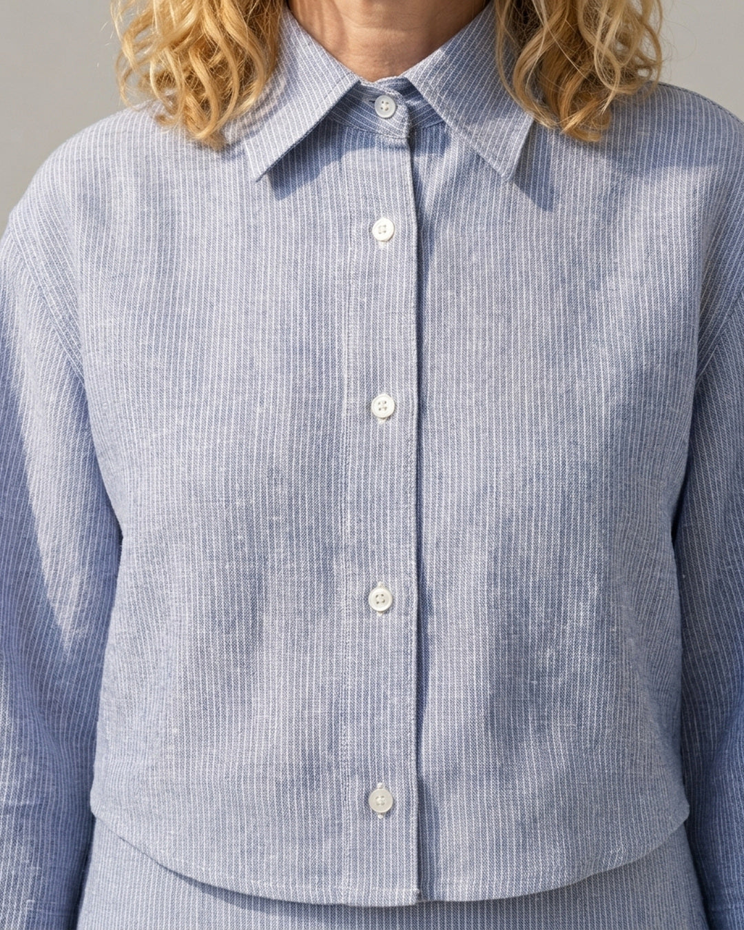 Close-up of the Cove Linen Crop Shirt showing the classic collar, button front placket and fine blue and white stripe