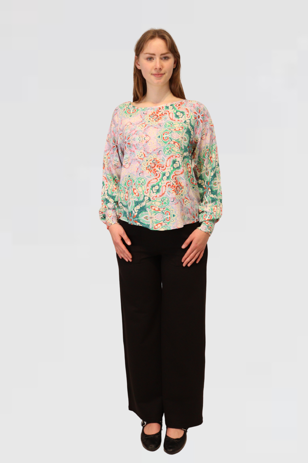 Model wearing the Reca Paisley Bloom Blouse, a long sleeve  blouse with paisley design, styled with black pants 