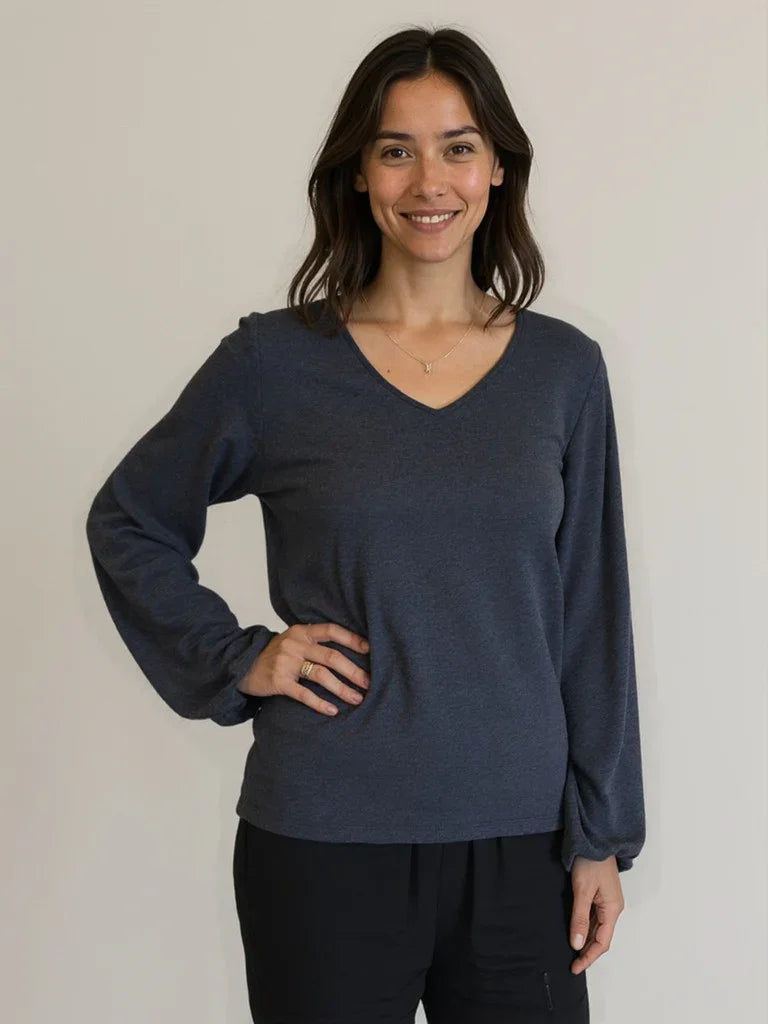 AI Model wearing Reca Bishop Blouse in Ink with V-neckline and long bishop sleeves, styled with black trousers, angled view.