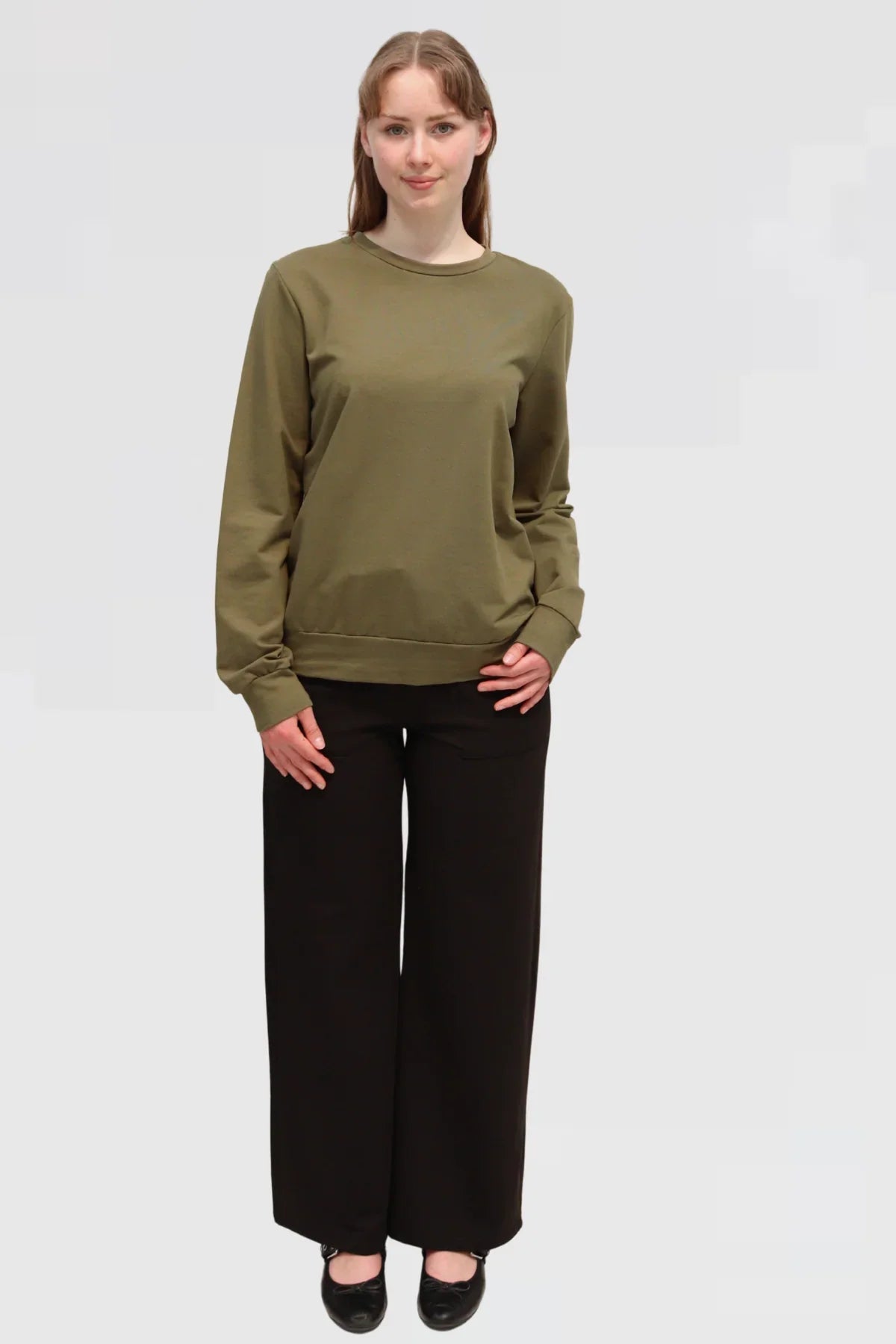 Front view of Reca Organic Cotton Sweater in olive styled with black drape trousers, full outfit.