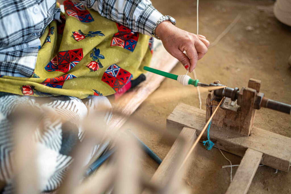 A person working with thread using traditional hand-operated equipment